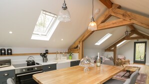 Une cuisine moderne avec une table en bois, des chaises grises et une lucarne.