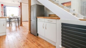 Una cocina moderna con un refrigerador empotrado, armarios de madera y una escalera de cristal que conduce a un nivel superior.