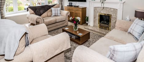 A living room with a sofa set, a coffee table, a fireplace, and a television.