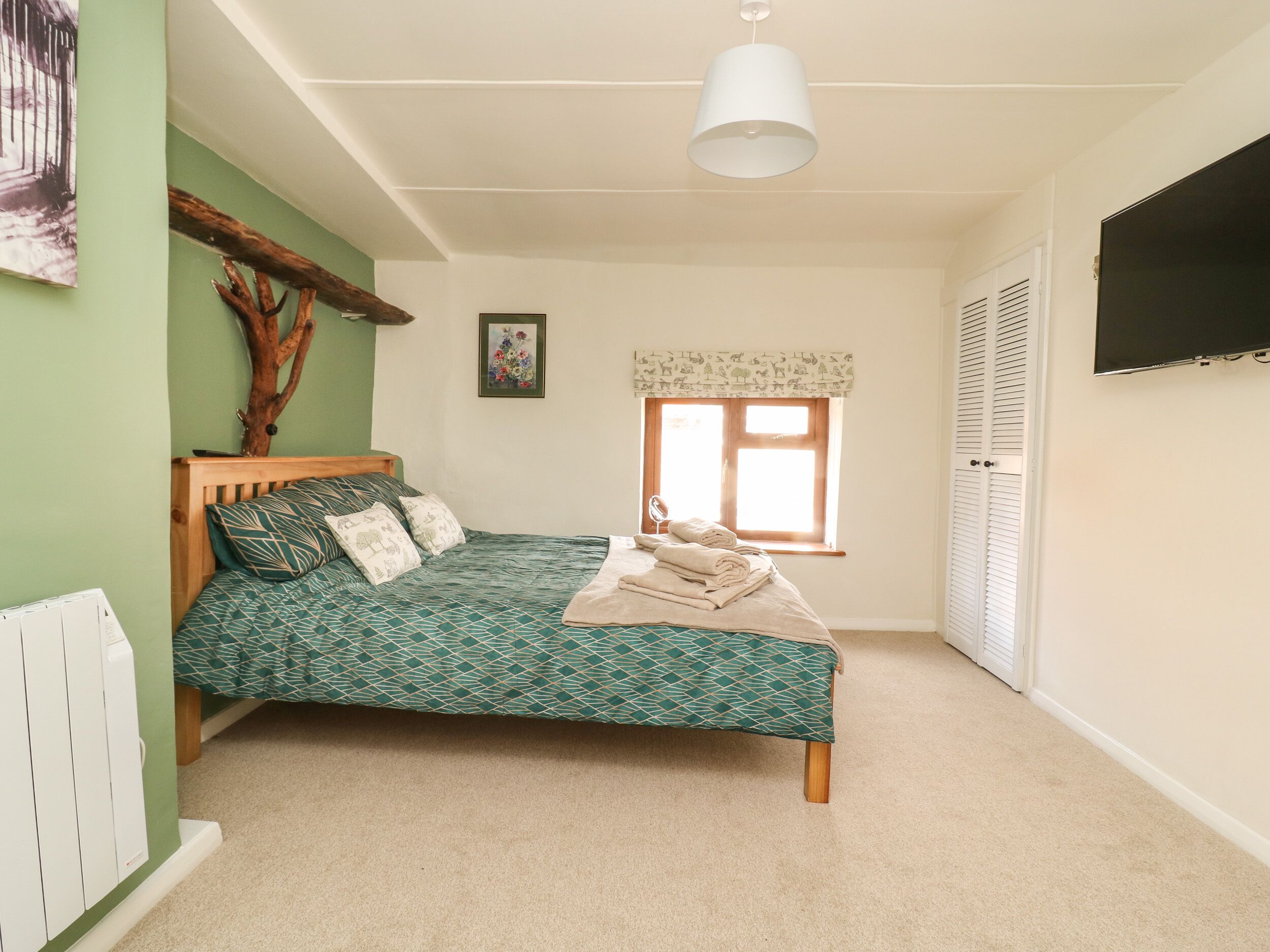 Un dormitorio con cama, ventana, radiador y televisor.