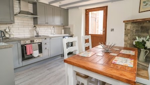 Una cucina con mobili grigi, un tavolo in legno e un camino in pietra.
