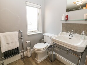 A bathroom with a toilet, sink, and window. - Archway Cottage (Matlock)