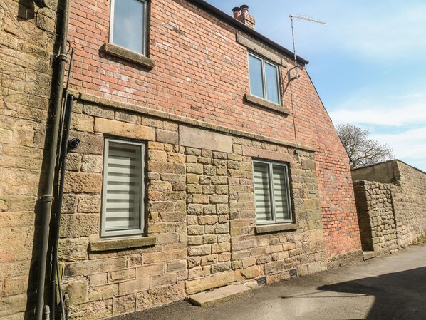 A two-story stone building with two windows, a chimney, and a visible antenna. - Archway Cottage (Matlock)