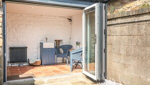 Un espace patio doté d’un sol en pierre, d’une chaise en osier bleue, d’un meuble blanc et d’un radiateur.