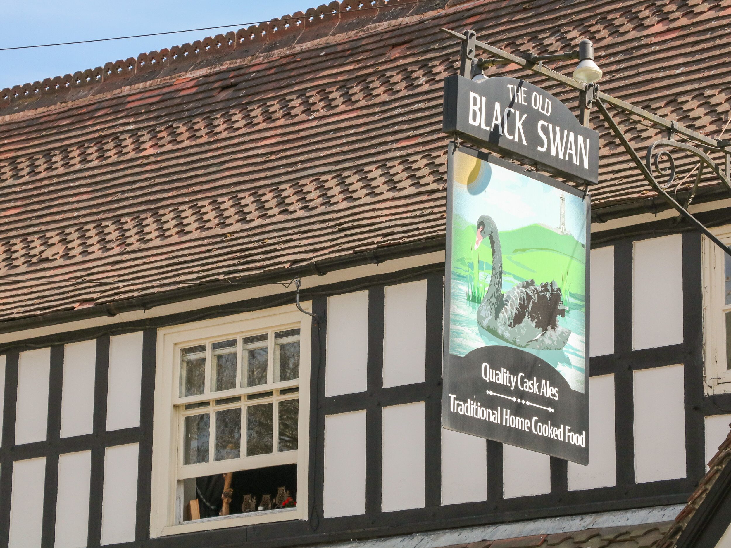 A sign for 'The Old Black Swan' with a swan illustration and mentions 'Quality Cask Ales' and 'Traditional Home Cooked Food'.