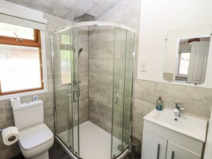 Une salle de bain moderne avec une douche à parois de verre, des toilettes, un lavabo et un miroir.
