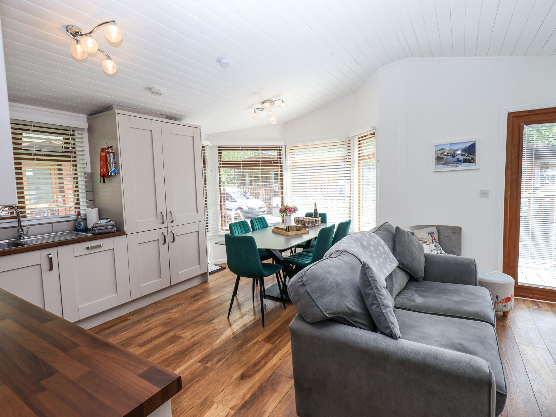 A modern kitchen with white cabinets, a wooden countertop, and a dining area with a table and chairs.