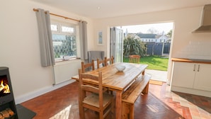 A spacious kitchen with a wooden dining table, a built-in stove, and a view of the garden.