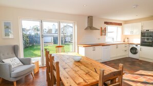 A spacious kitchen with a wooden table and chairs, a dishwasher, and a washing machine.