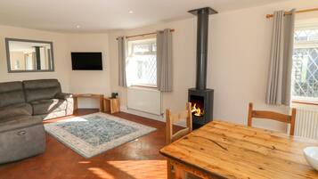 Ein Wohnzimmer mit einer Couch, einem Holztisch, einem Kamin und einem Fernseher.