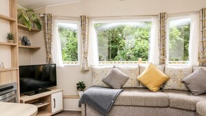 A cozy living room with a sofa, TV, and a small plant. - Ochenta (Ilfracombe)