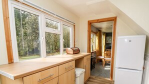 Una cocina funcional con armarios de madera, un refrigerador blanco y una ventana con vistas a un jardín.