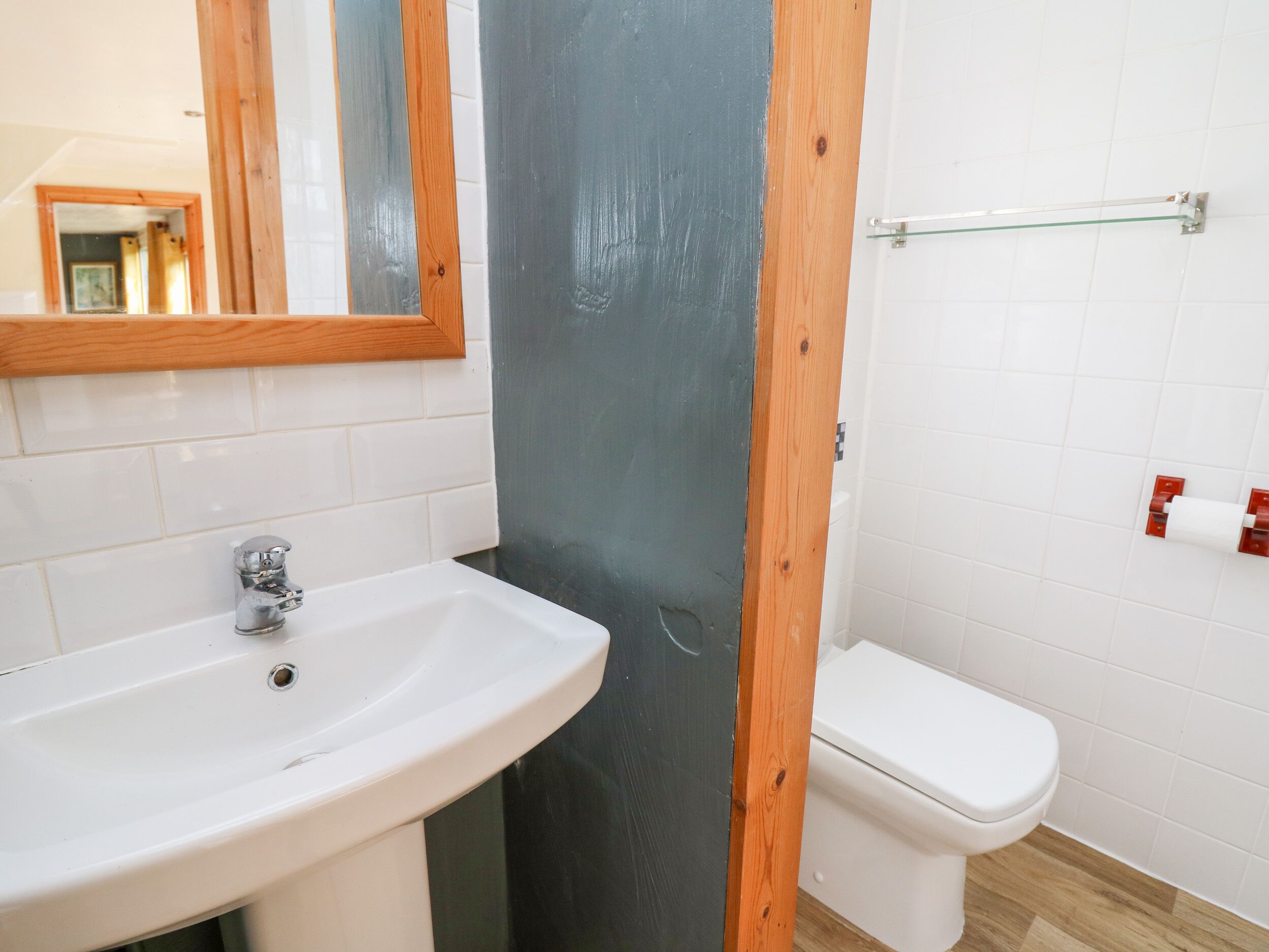 A bathroom with a white sink, a toilet, and a mirror.