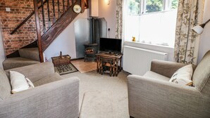 A cozy living room with a fireplace, a television, and comfortable seating. - The Mill Wheel (Ashbourne)
