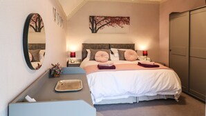A neatly arranged bedroom with a bed, bedside tables, a mirror, and a wardrobe. - The Mill Wheel (Ashbourne)