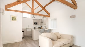 A modern kitchen with white cabinetry, a central island, and a dining area with two chairs. - Laurel Farm (Malton)