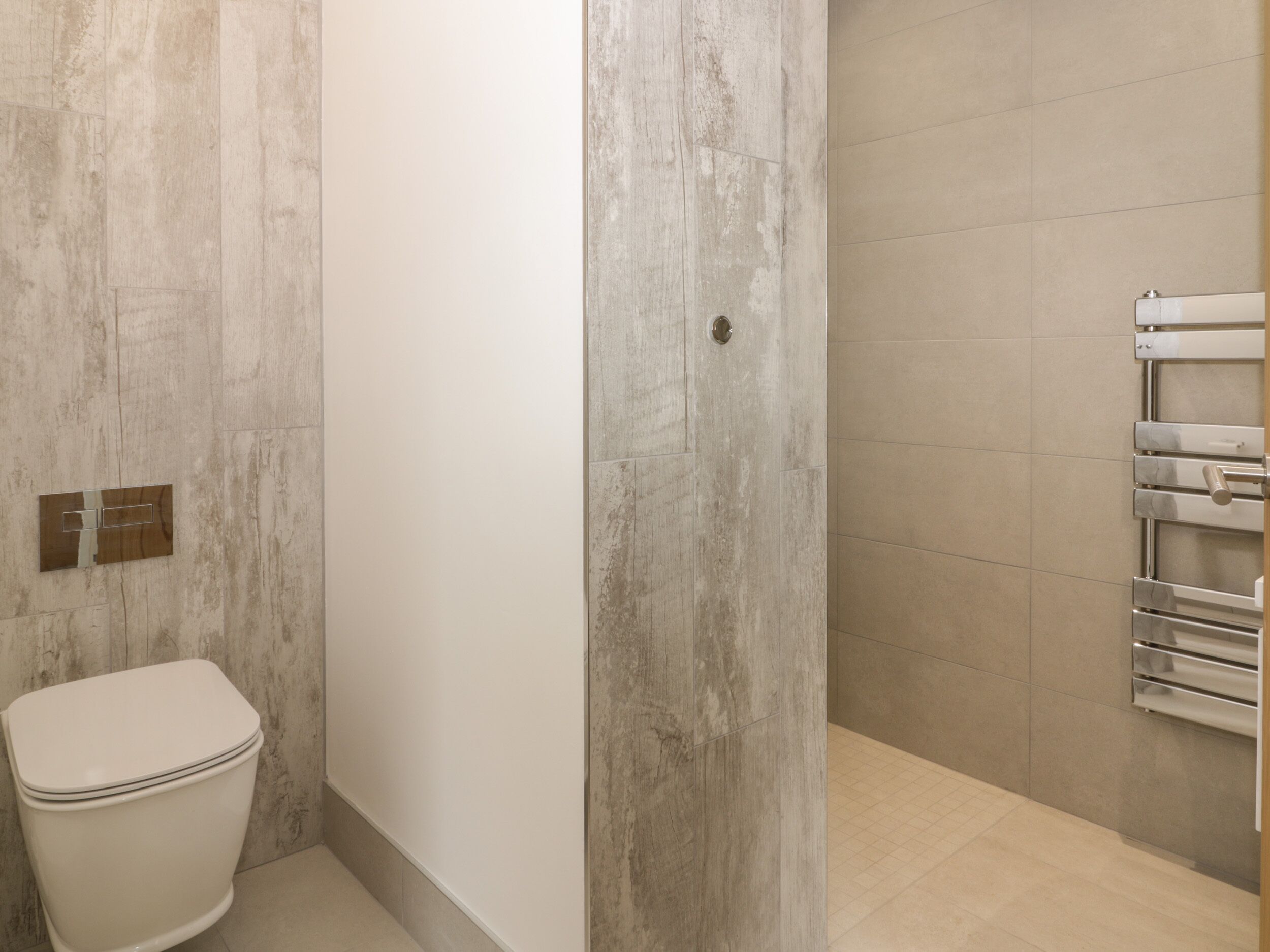 Ein Badezimmer mit Toilette, Handtuchhalter und Duschbereich.