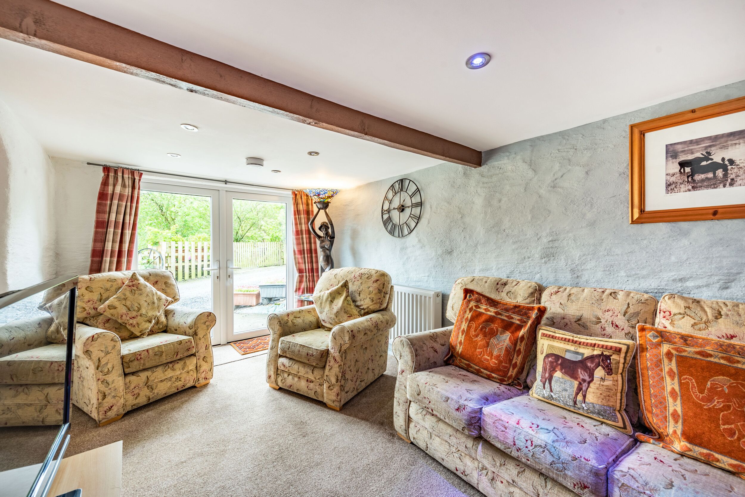 A living room with a sofa, two armchairs, a clock, and a framed picture on the wall.