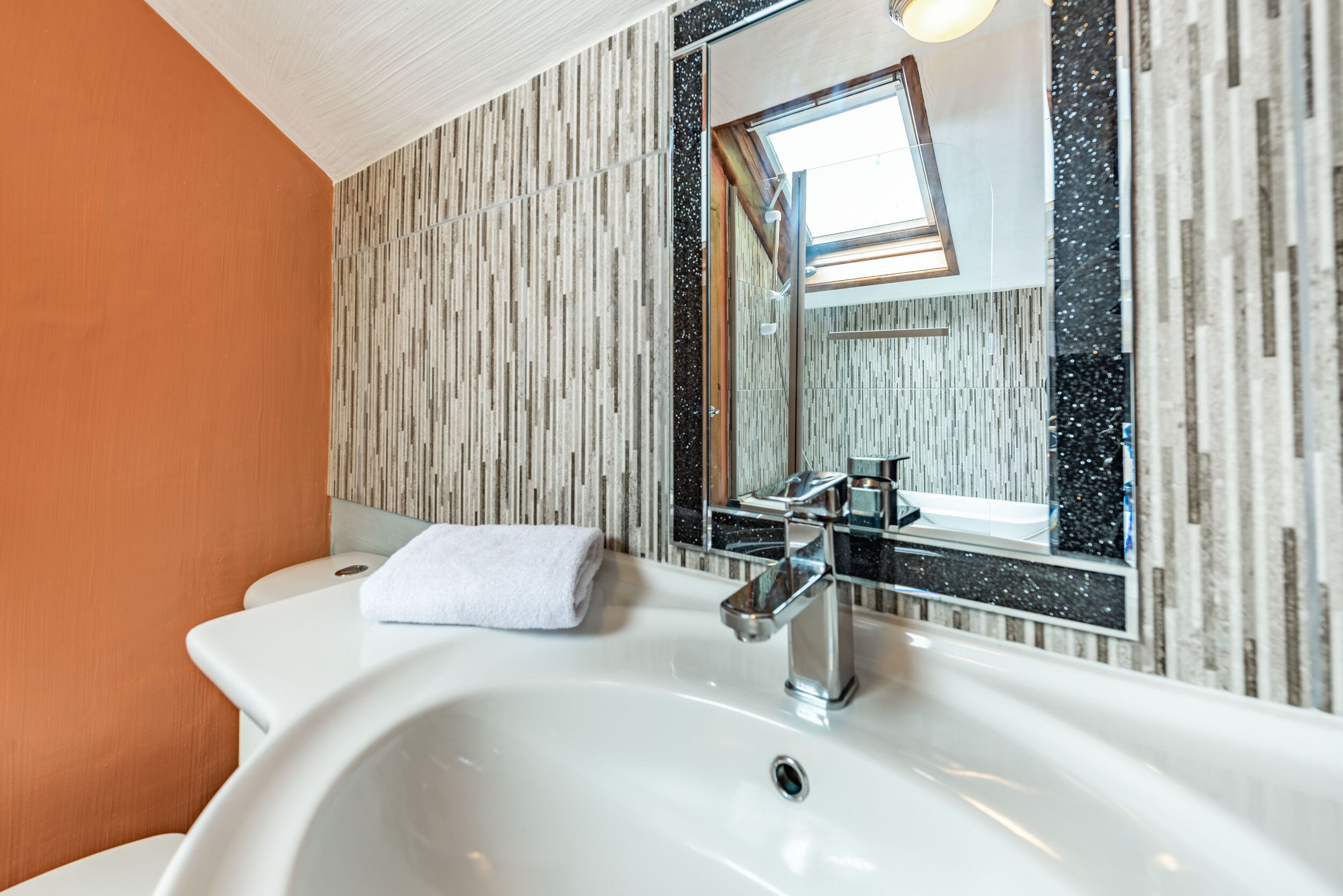 Un baño moderno con un lavamanos blanco, un espejo y una toalla sobre el mostrador.