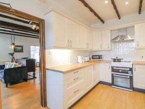 A modern kitchen with white cabinets, a wooden countertop, a microwave, a stove, and a large oven. - The Brewery (Weymouth)