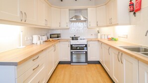 Een moderne keuken met witte kasten, houten aanrechtbladen, een roestvrijstalen spoelbak en een ingebouwde oven.
