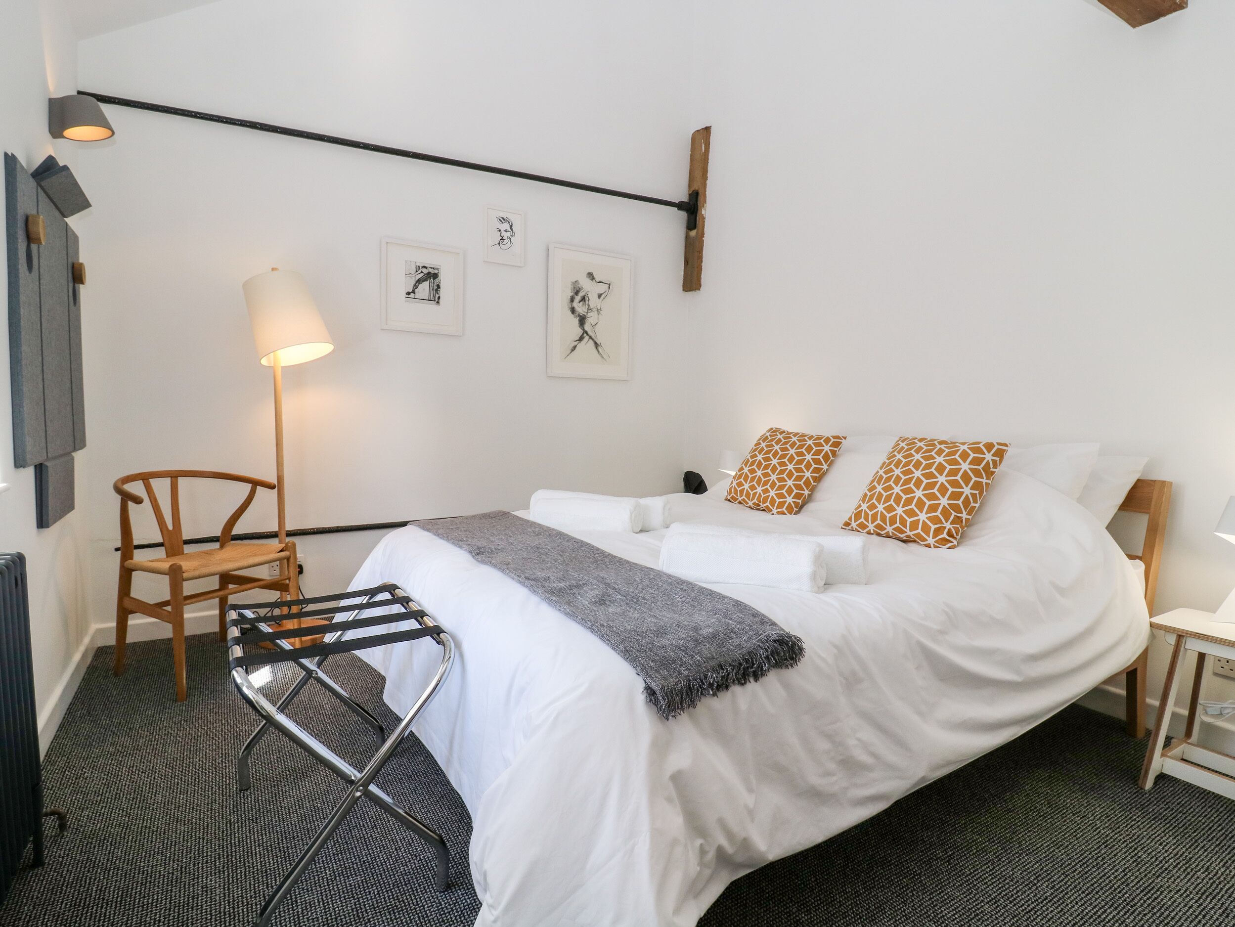 A neatly arranged hotel room with a bed, a chair, a lamp, and artwork on the wall.