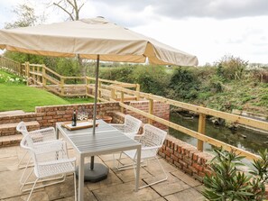 A patio with a table and chairs, a wooden bridge, and a pond. - The Pump House Art Studio (Doncaster)