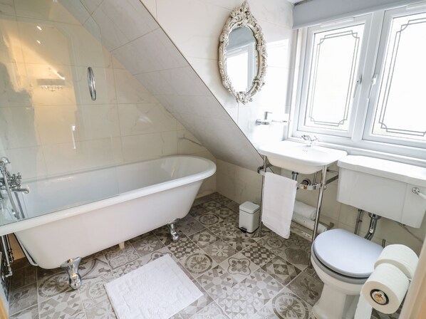 Une salle de bain avec une baignoire sur pieds, un lavabo, des toilettes et un miroir.