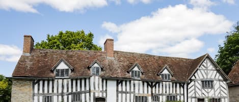 A traditional half-timbered house with a stone wall and a wooden gate.