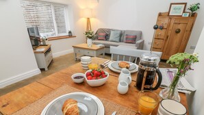 A breakfast setup with croissants, strawberries, and coffee on a wooden table. - Horncop Nook (Kendal)