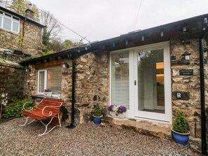 Un bâtiment en pierre avec un banc en bois et des plantes en pot.