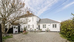 A white building with a gravel driveway, a small garden with potted plants, and a sign reading "Bishop's Way". - Badgers Way (Tintagel)