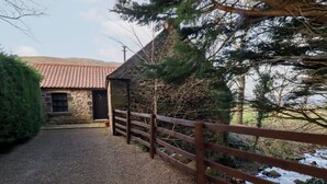 A gravel driveway leading to a stone building with a tiled roof. - The Smithy (Wooler)