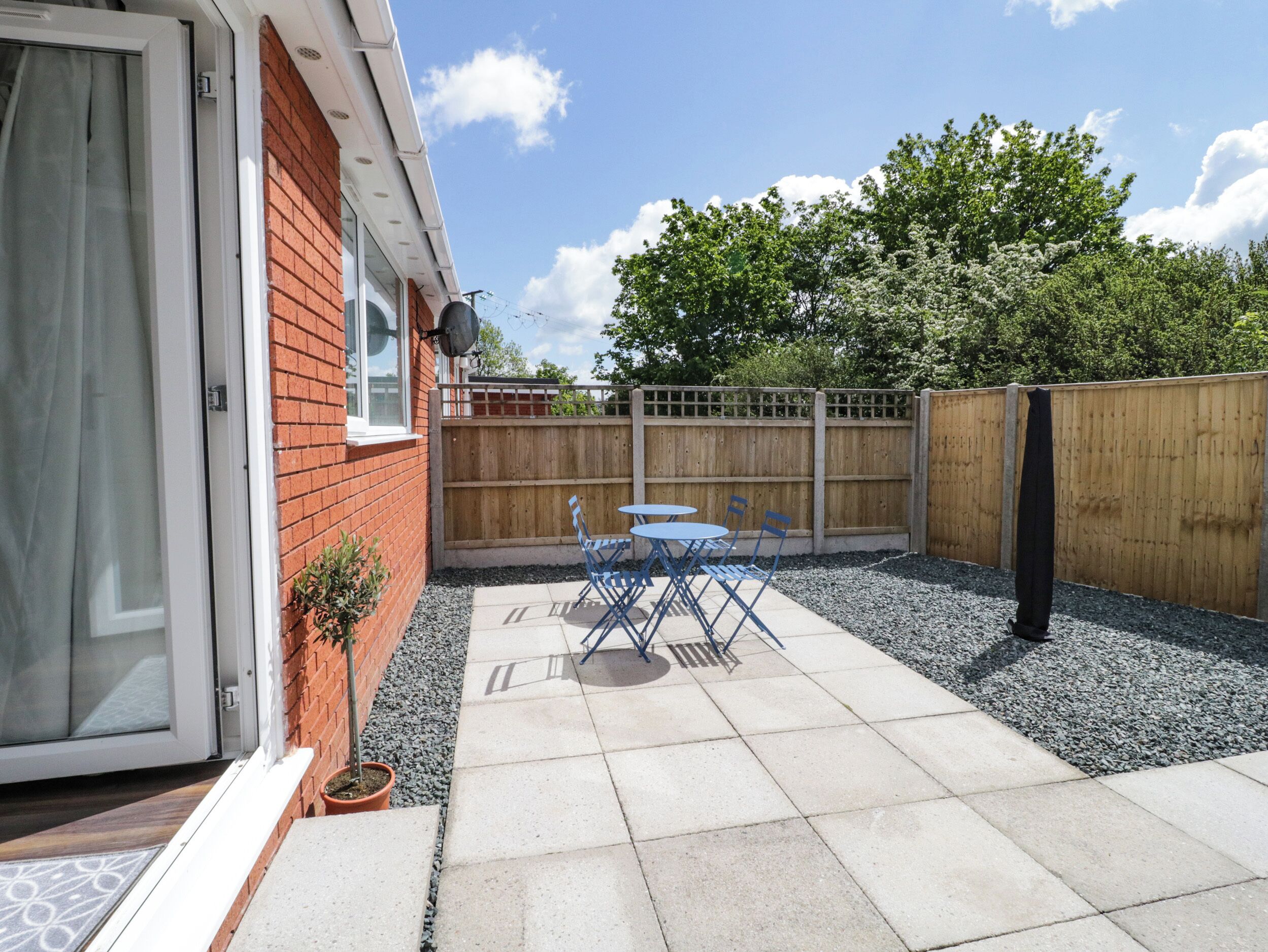 A patio with a table and chairs, a wooden fence, and a brick wall.