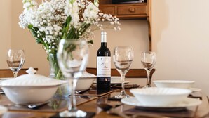A dining table set with white dishes, a bottle of wine, and a vase of flowers. - Blueberry Cottage (Wooler)