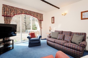A living room with a television, a sofa, a chair, and a lamp.