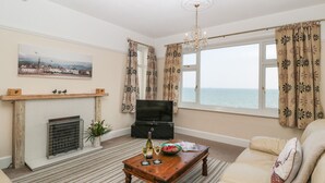 Un salon avec une cheminée, un téléviseur, un canapé et une vue sur la mer.