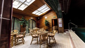 An indoor seating area with tables and chairs, a pool, and a skylight.