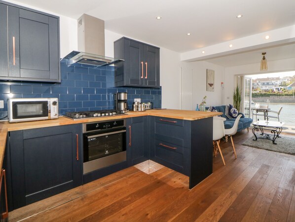 A modern kitchen with dark blue cabinets, a microwave, stove, and oven.