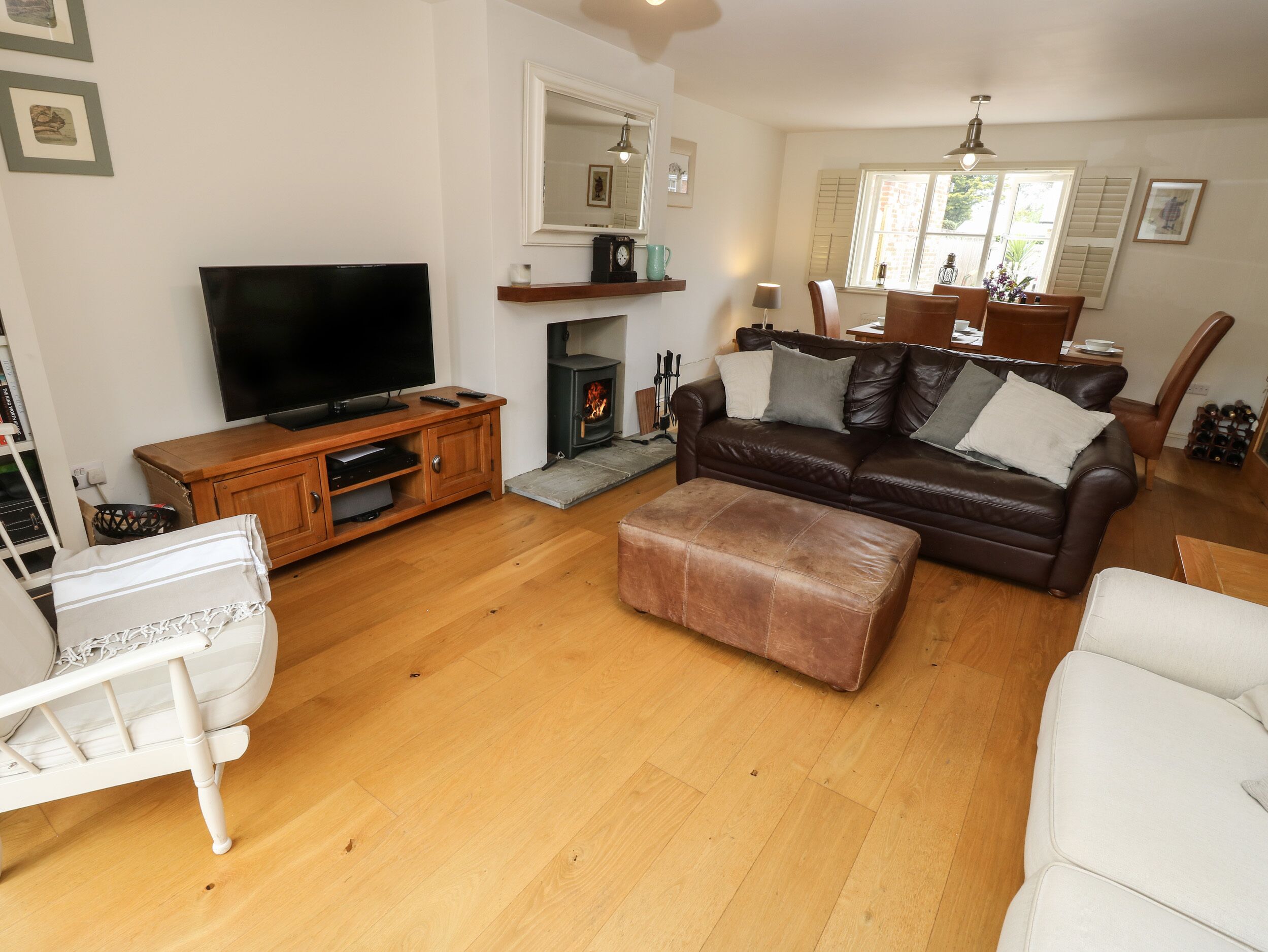A living room with a TV, wooden entertainment unit, leather sofa, ottoman, and a fireplace.