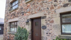 A stone building with a wooden door, a window, and a sign that reads "Ivy Cottage 14".