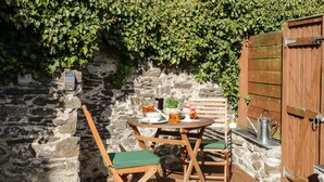 A wooden deck with a stone wall and a wooden gate.