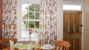 A dining table with plates, glasses, and a vase of flowers. - Mount Pleasant Cottage (Grange-over-Sands)