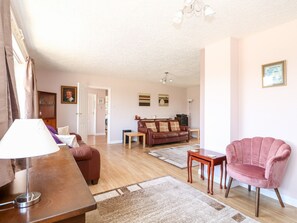 A living room with a brown leather sofa, a pink armchair, a wooden coffee table, and a lamp. - The Hemploe (Mablethorpe)