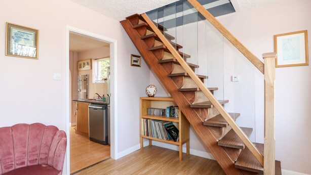 Un salon moderne avec un escalier en bois, un canapé rouge et une bibliothèque.