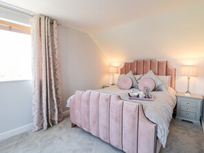 Une chambre à coucher avec un lit, des tables de chevet et une fenêtre avec des rideaux.