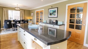 A modern kitchen with a curved island, wooden cabinets, and a dining area with black upholstered chairs.