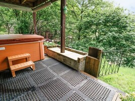 Zona de hidromasaje con banco de madera, repisa de piedra y valla metálica.