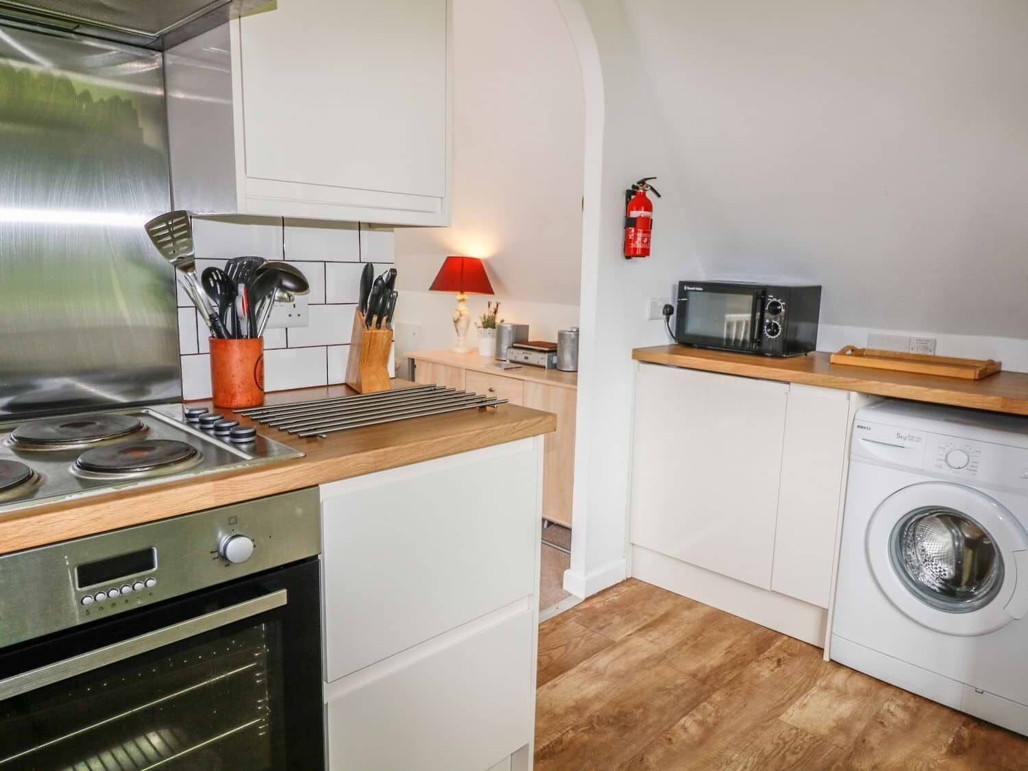 A compact kitchen with a stove, oven, microwave, and washing machine.