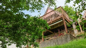 A wooden building with a balcony, surrounded by greenery and a stone wall. - 19 Honicombe Park (Gunnislake)
